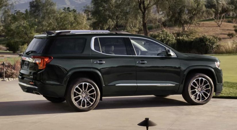 A black 2022 GMC Acadia Denali is shown from the side parked in a driveway after leaving a GMC Acadia dealer.
