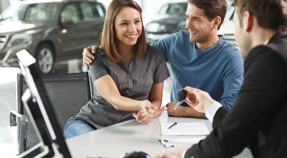 A couple is shown finishing paperwork at a Nissan Dealer.