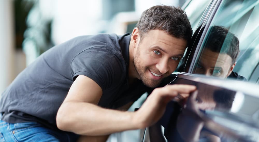 A person is shown inspecting the exterior of a car.