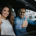 A couple is shown giving a thumbs up inside of a car after they leaned how to sell your car.