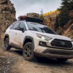 A white 2022 Toyota RAV4 TRD is shown from the front off-roading in the mountains after leaving a Toyota dealer.