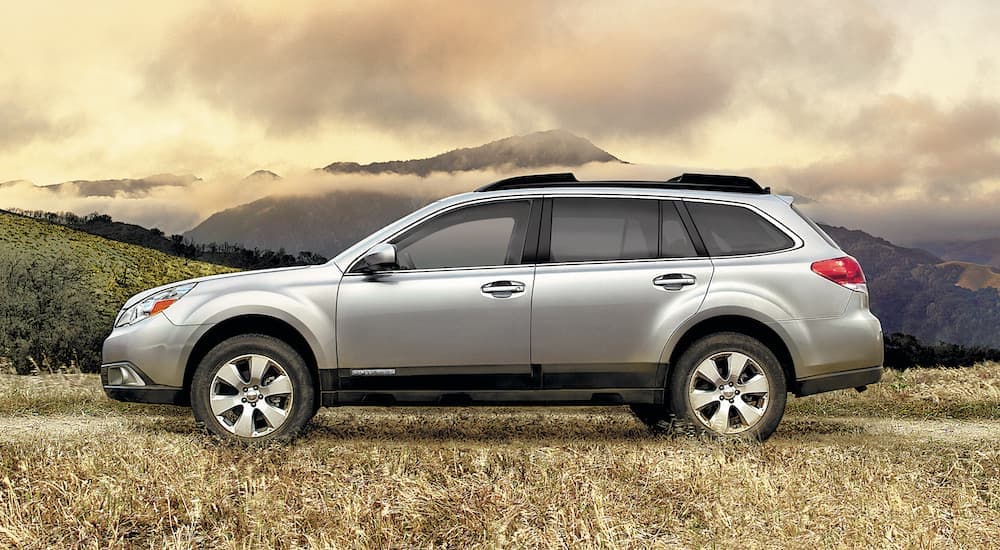 A silver 2010 Subaru Outback is shown from the side parked in a field.