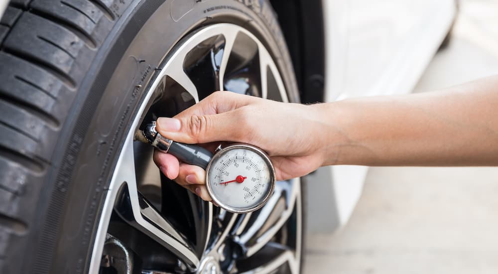 A person is checking the tire pressure on a vehicle.