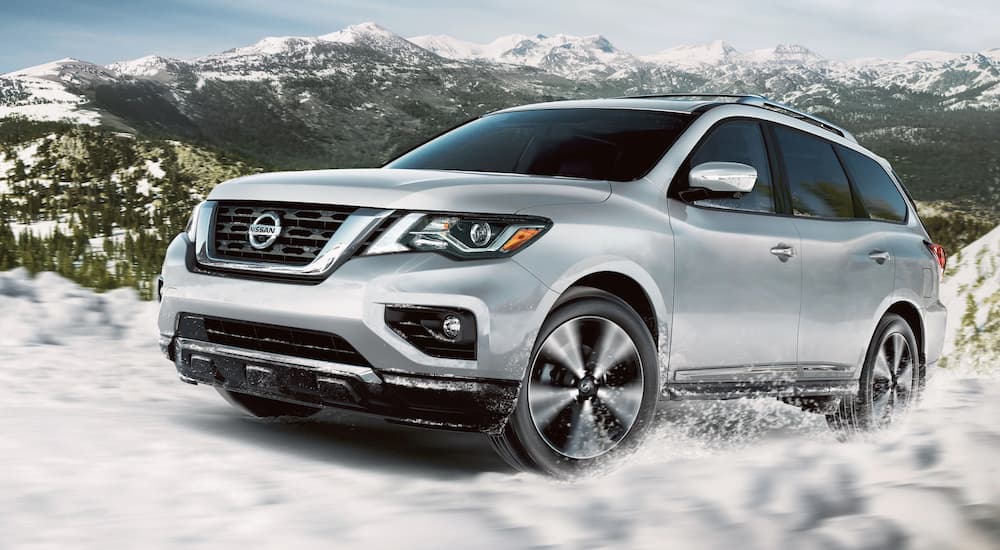 A silver 2020 Nissan Pathfinder is shown from the side off-roading in the snow.