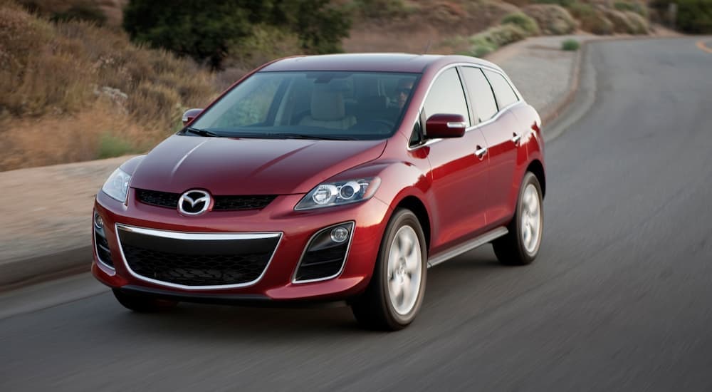 A red 2011 Mazda CX-7 is shown from the front driving on an open road.