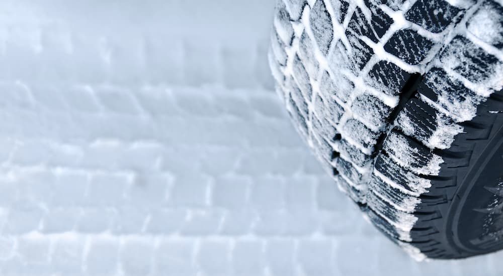 A tire is shown in close up driving in the snow.
