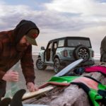 A group of friends are shown near a light blue 2021 Ford Bronco Outer Banks on a beach.