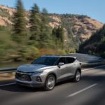 A silver 2022 Chevy Blazer Premier is shown driving on a highway through the mountains.