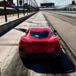 A red 2022 Chevy Corvette Stingray is shown from the rear on a racetrack.