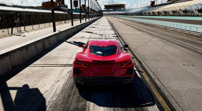 A red 2022 Chevy Corvette Stingray is shown from the rear on a racetrack.