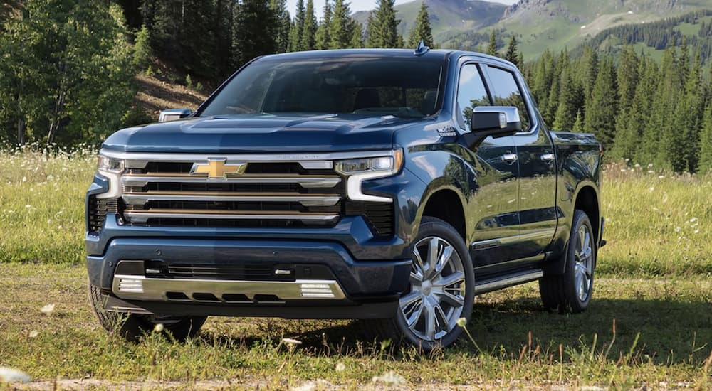 A blue 2022 Chevy Silverado 1500 High Country is shown from the front parked in a field.