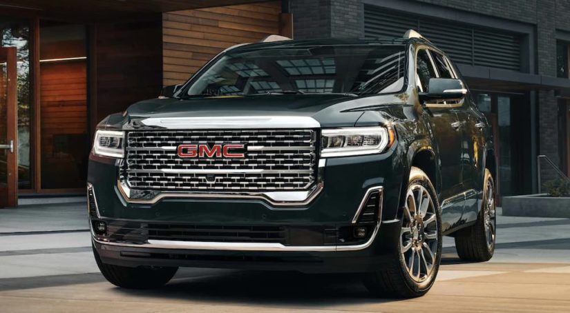 A black 2022 GMC Acadia Denali is shown parked outside of a modern home.
