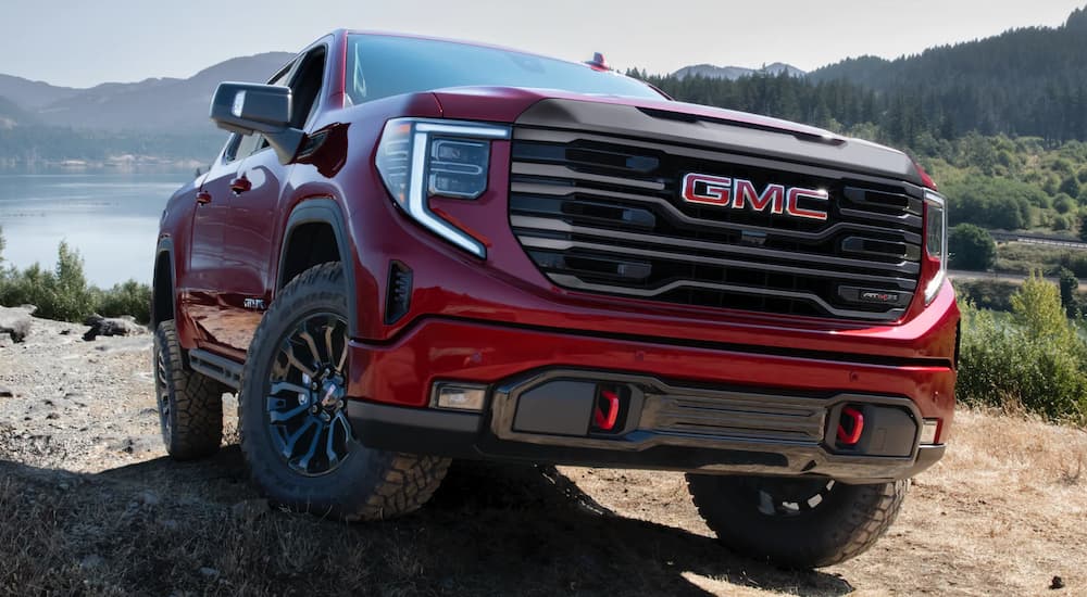 A red 2022 GMC Sierra 1500 AT4X is shown off-roading on a rocky trail.