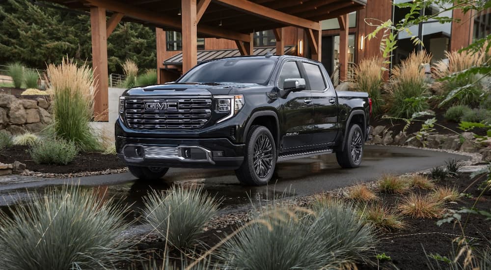 A black 2022 GMC Sierra 1500 Denali Ultimate is shown parked outside of a modern home.