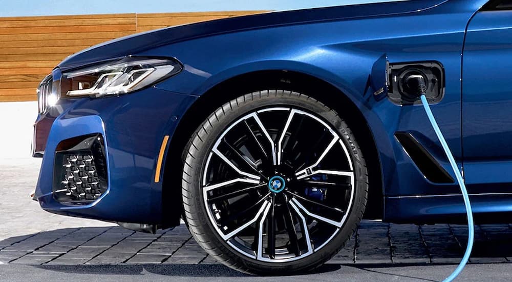 A close up shows a blue 2022 BMW 7-Series is shown plugged into a charger.
