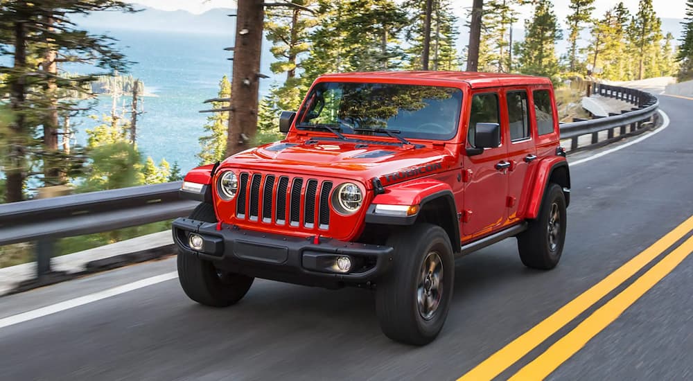 A red 2022 Jeep Wrangler Rubicon is shown driving down an empty road.