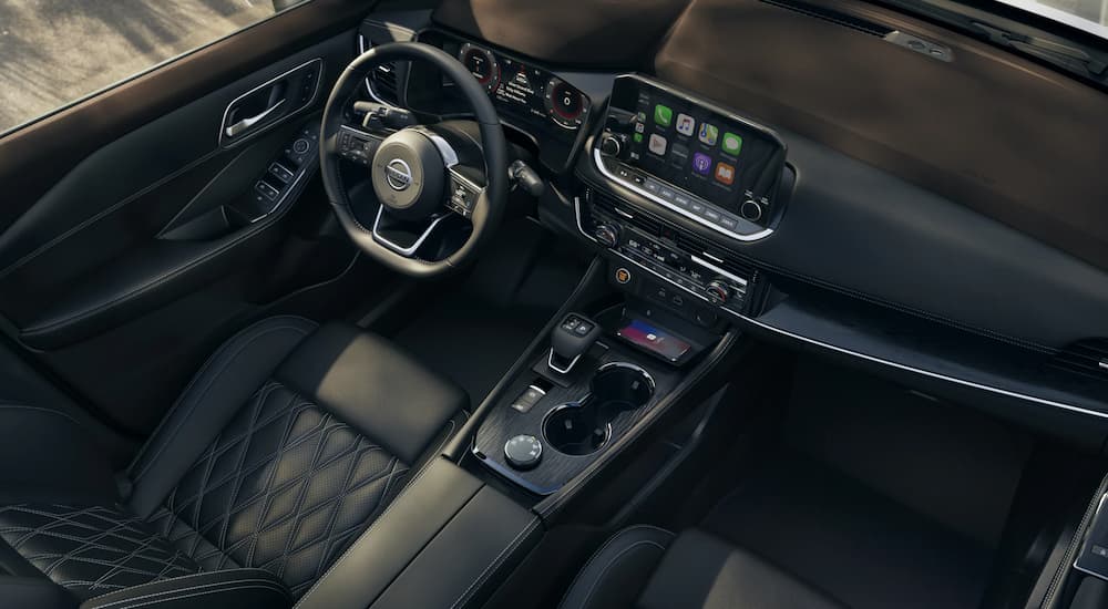The black interior of a 2022 Nissan Rogue shows the steering wheel and center console.