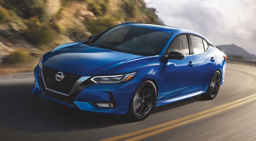 A blue 2022 Nissan Sentra is shown on a highway during a 2022 Nissan Sentra vs the 2022 Honda Civic comparison.