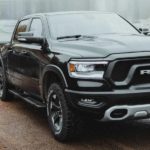 A black 2022 Ram 1500 is shown towing a boat trailer out of a body of water.