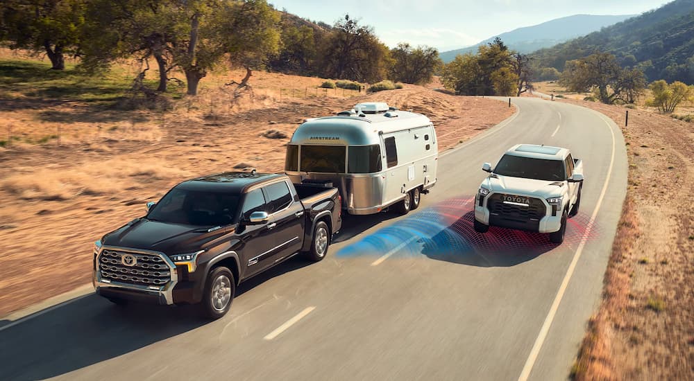 A black 2022 Toyota Tundra is shown towing an Airstream with simulated blind spot monitor sensor lines.