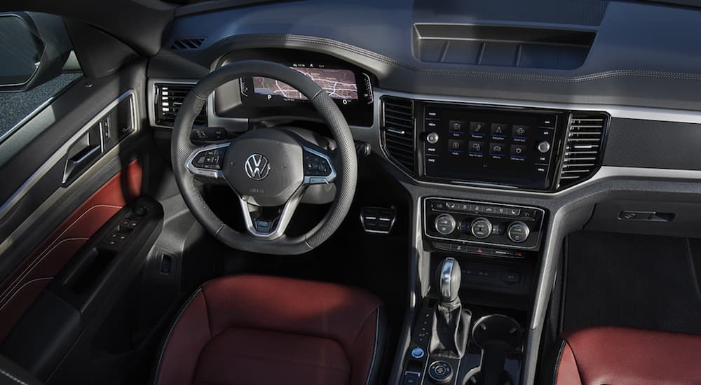 the grey and red interior of a 2022 Volkswagen Atlas Cross Sport V6 SEL Premium R-Line shows the steering wheel and infotainment screen.