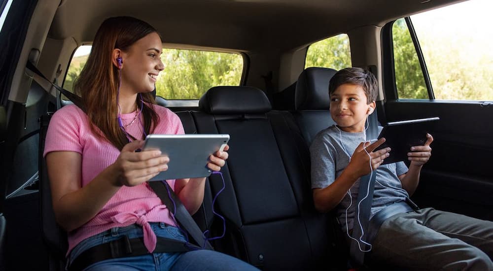 Two kids are shown in the back seat of a 2022 Volkswagen Tiguan using tablets.
