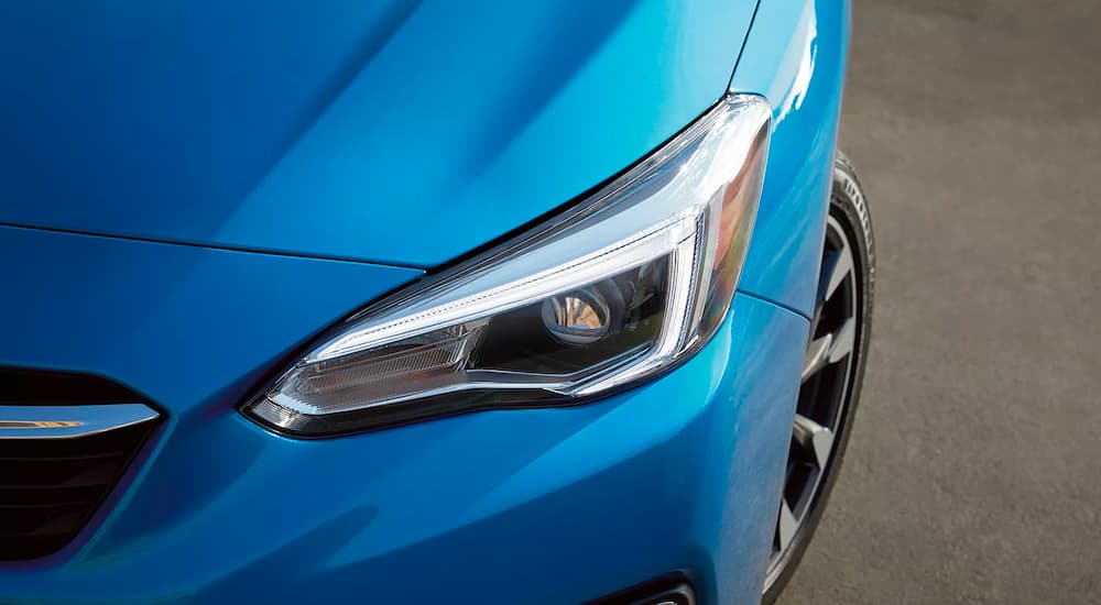 A close up shows the driver side headlight on a blue 2023 Subaru Impreza.