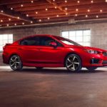A red 2023 Subaru Impreza is shown from the side in a garage.