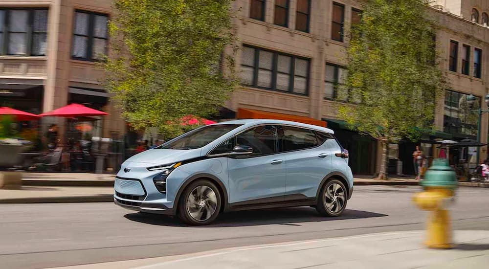 A light blue 2022 Chevy Bolt EV is shown driving on a city street.