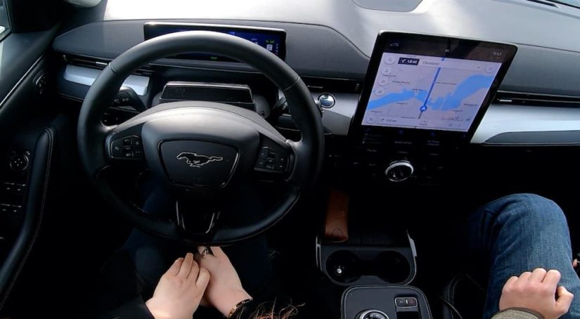 The black interior of a 2022 Ford Mustang Mach-E shows the steering wheel and infotainment screen.