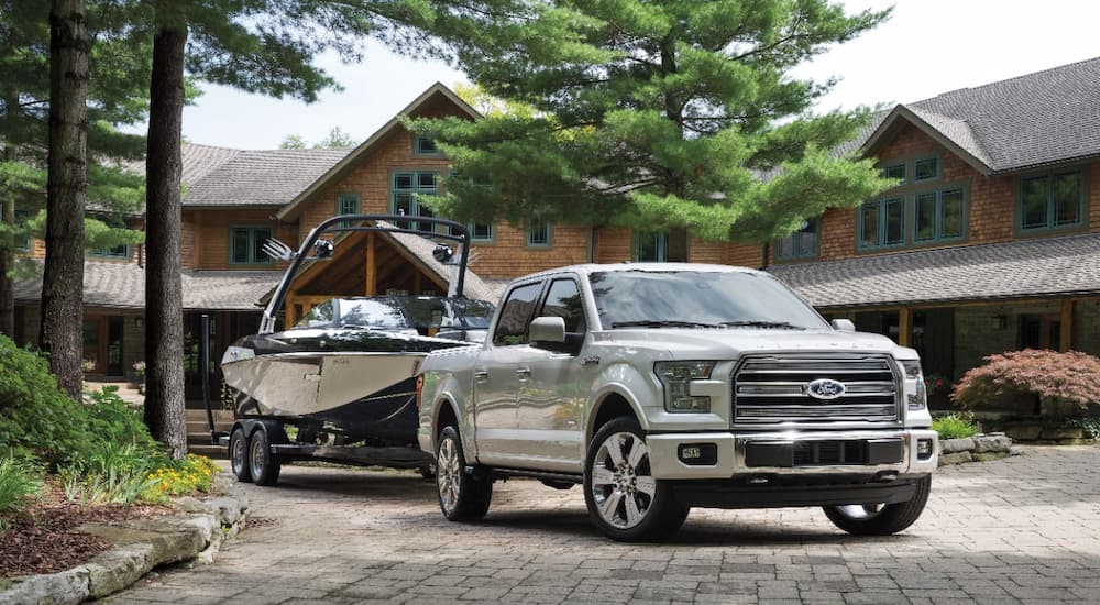 A white 2016 Ford F-150 Limited is shown towing a boat after leaving a certified pre-owned Ford F-150 dealership.
