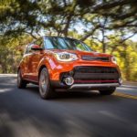 An orange 2019 Kia Soul is shown from the front driving on a an open road.