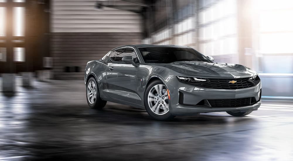 A grey 2022 Chevy Camaro LS is shown in a garage at a Chevrolet dealership.
