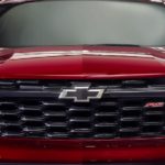 A close up shows the grille and headlights on a red 2024 Chevy Trax RS.