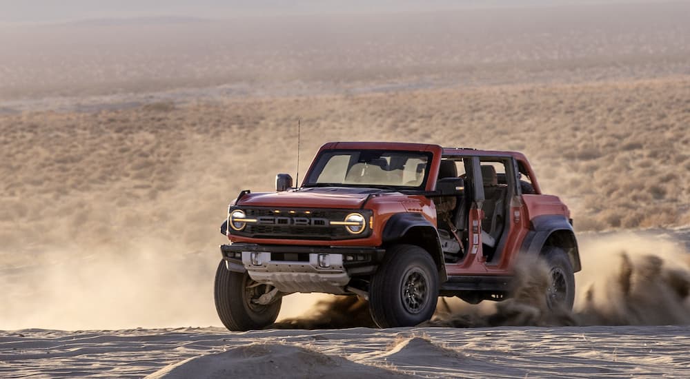 A red 2022 Ford Bronco Raptor is shown off-roading in the desert.