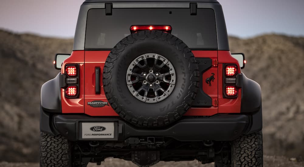 A red 2022 Ford Bronco Raptor is shown from the rear parked in the desert.