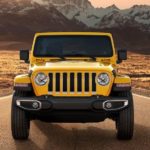A yellow 2021 Jeep Wrangler is shown from the front parked on a desert highway.