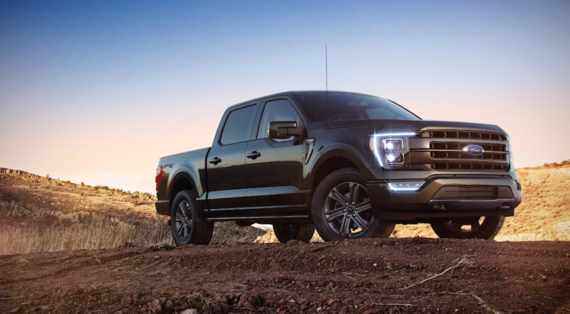 A black 2021 Ford F-150 Lariat is shown parked on trail during a sunset.