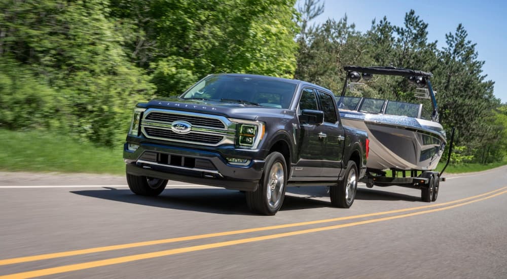 A black 2021 Ford F-150 Limited Hybrid is shown towing a boat.