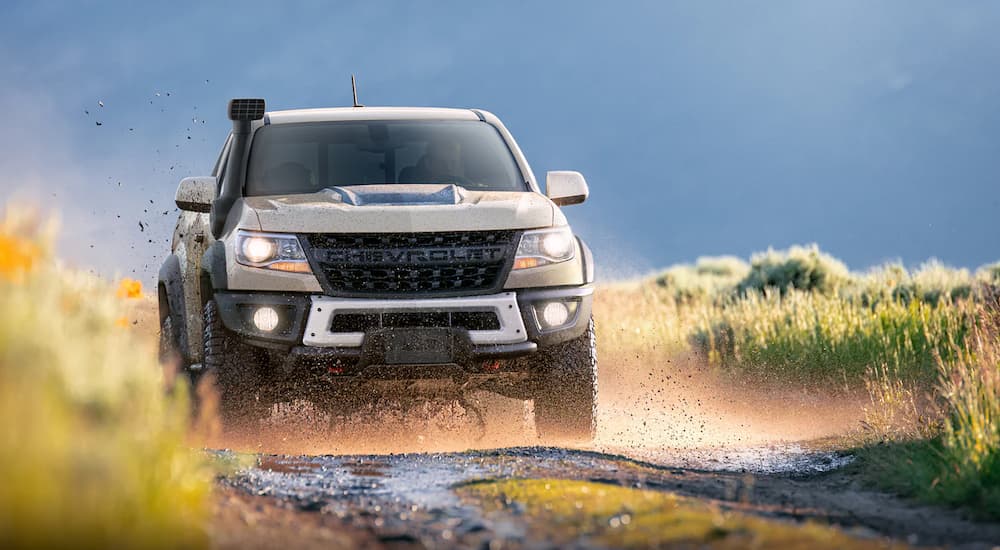 A tan 2022 Chevy Colorado ZR2 is shown off-roading on a muddy trail.