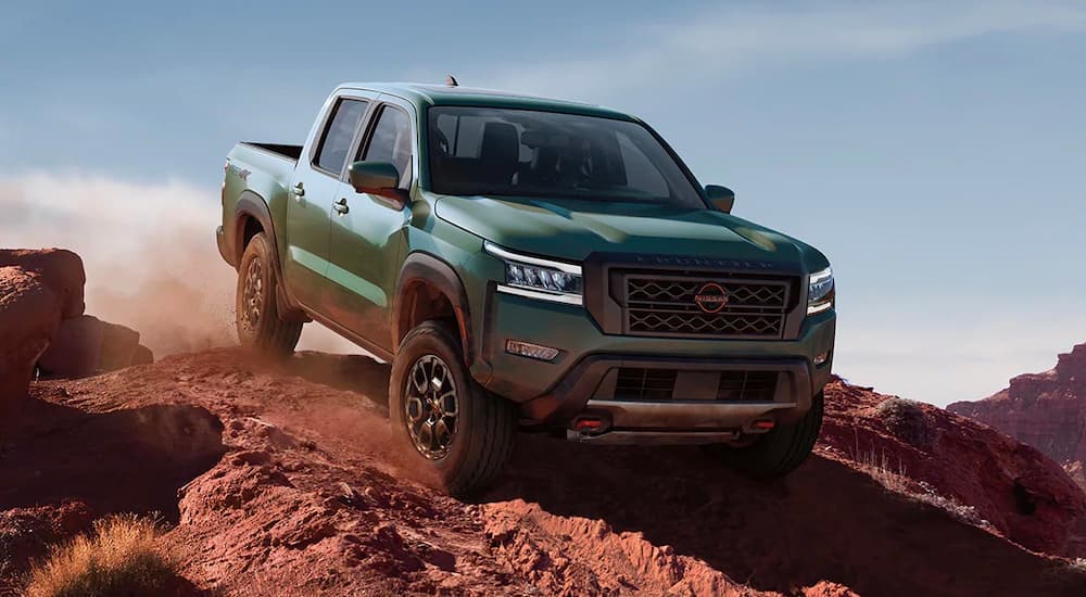 A green 2022 Nissan Frontier PRO-4X is shown off-roading on a dusty trail.
