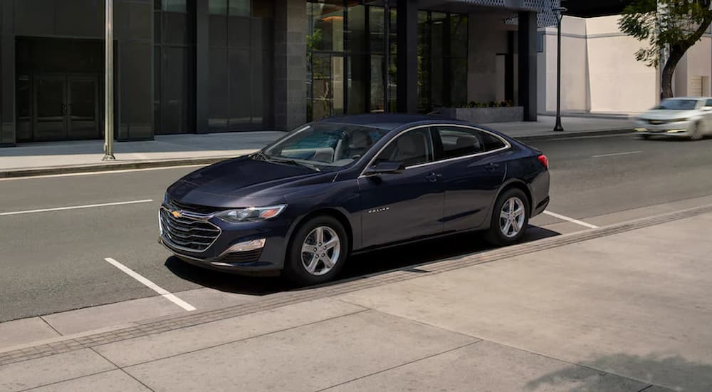 A gray 2022 Chevy Malibu is shown from the side parked on the side of the street.