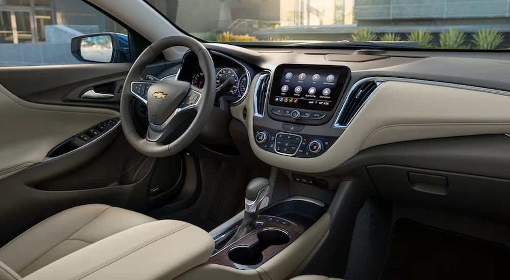 The tan and black interior of a 2022 Chevy Malibu shows the steering wheel and center console.
