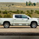 A white 2022 Chevy Silverado 1500 Limited High Country is shown from the side parked outside of a barn.