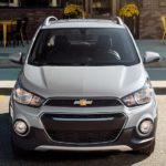 A silver 2022 Chevy Spark is shown from the front parked in front of a store.