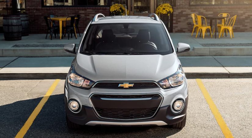 A silver 2022 Chevy Spark is shown from the front parked in front of a store.