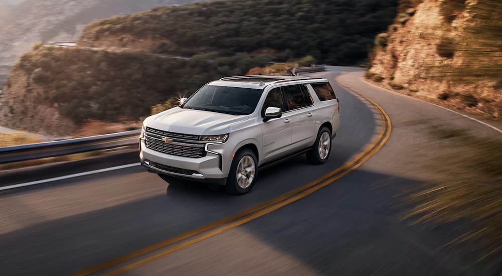 A white 2022 Chevy Suburban LT is shown driving on a mountain highway.