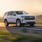 A white 2022 Chevy Tahoe Premier is shown driving on a winding road.