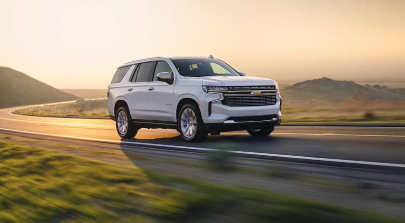 A white 2022 Chevy Tahoe Premier is shown driving on a winding road.