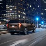 A brown 2022 Chevy Tahoe RST is shown driving on a city street at night.